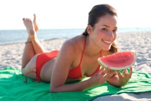 Woman eating a water melon on the beach